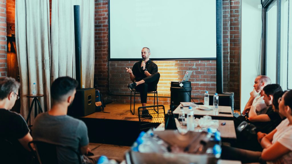 pranayama A business seminar with a speaker addressing an attentive audience in a modern conference setting.