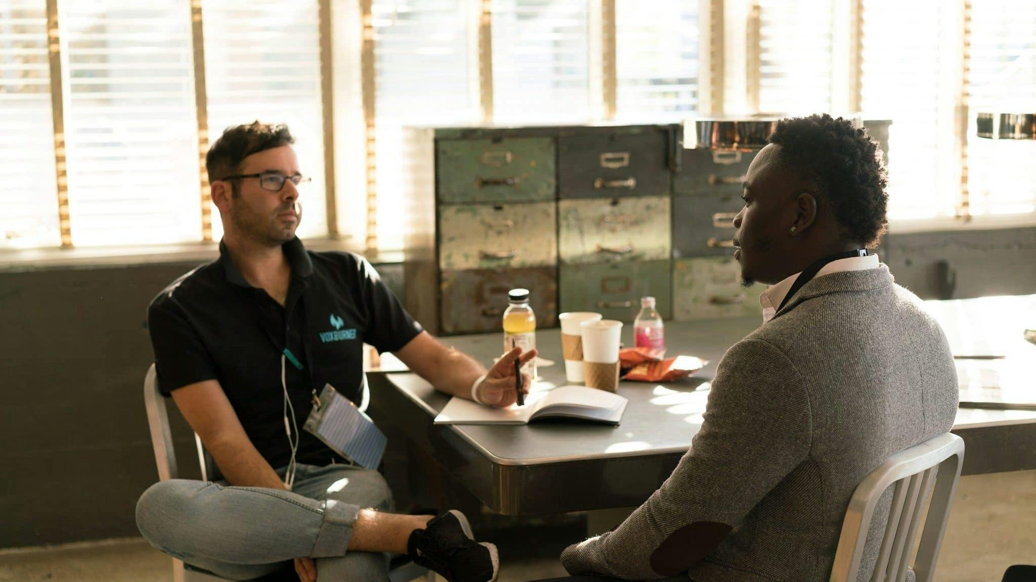 yoga Two men having a focused business discussion in a sunlit office space.